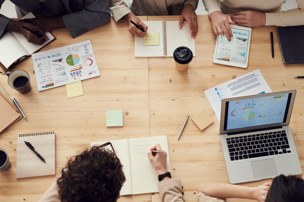equipo de trabajo debatiendo el tono de voz de una marca con portátiles y notas